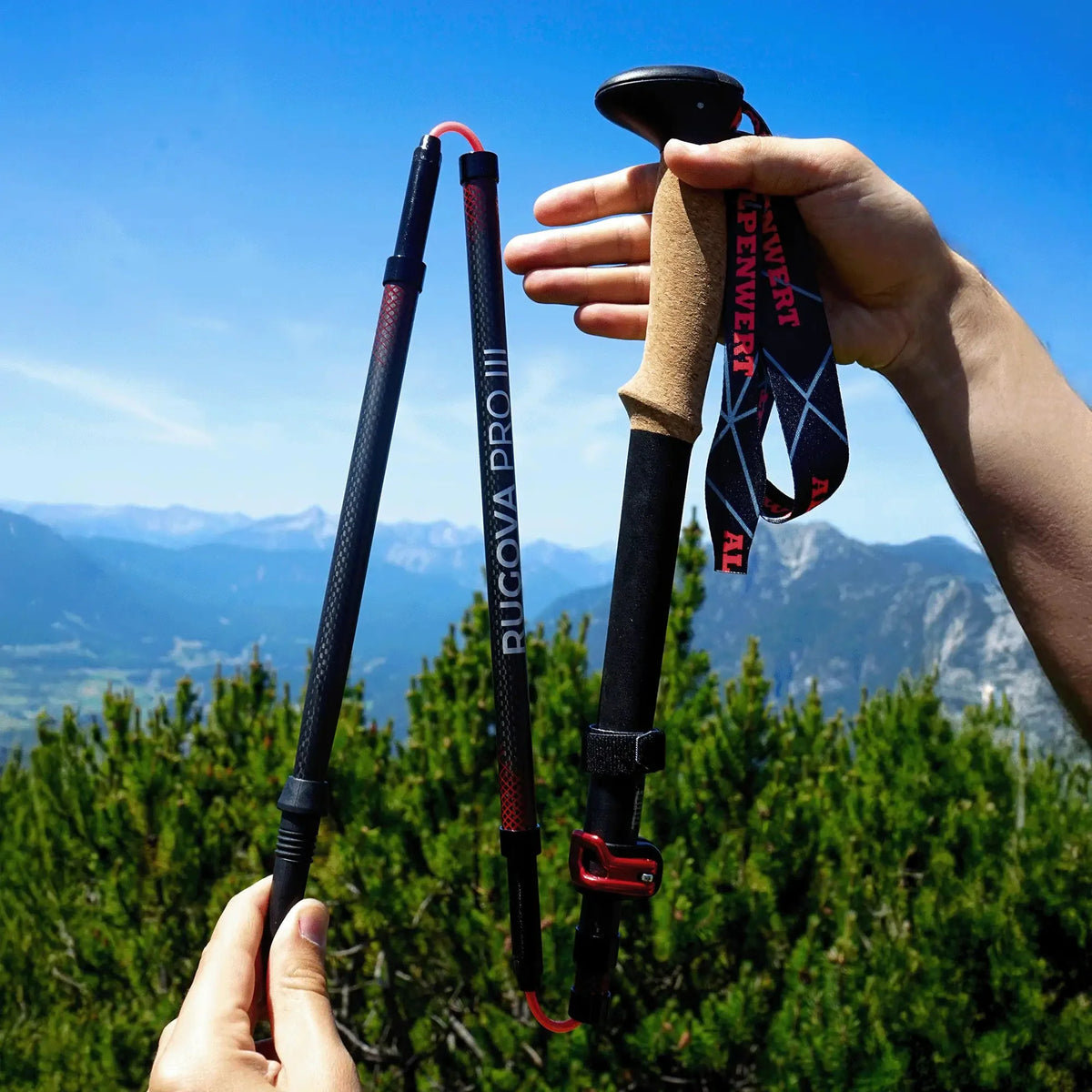 Zwei Hände setzen einen zusammengelegten Alpenwert Faltstock vor Bergpanorama zusammen